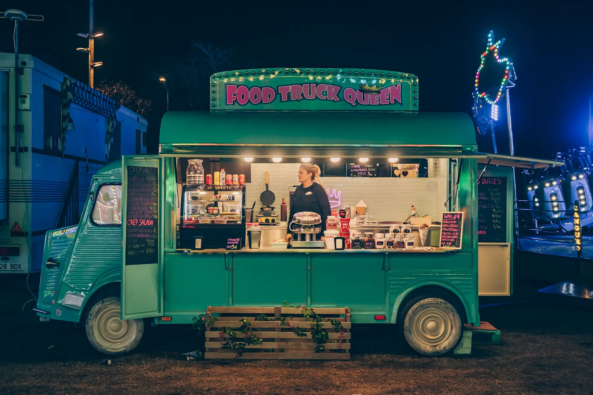 Vintage green food van trading at a night market with its serving hatch open and the operator at the counter